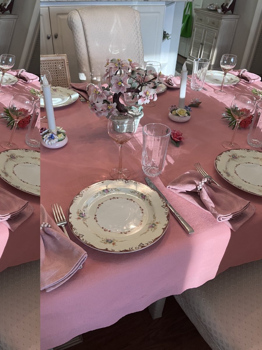 A pink table setting with floral china, flowers, and crystal glasses.